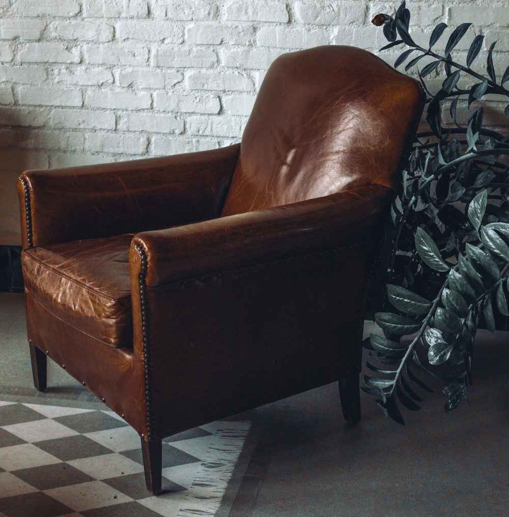 Leather Furniture: Enduring Luxury for Elevated Living 6 mickler-co-design-studio-carolina-beach-nc-luxury-leather-furniture-high-quality-leather-chair-by-plant-brick-wall-distinct-home-staging